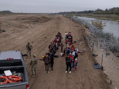 Migrantes esperan para ser procesados, luego de cruzar el río Bravo, en Eagle Pass (Texas).