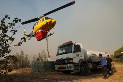 Un helicóptero recoge agua para sofocar el incendio en Penteli, al noroeste de Atenas, este lunes.