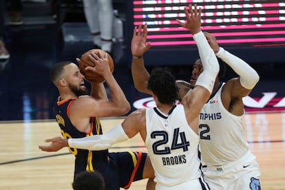 Stephen Curry intenta lanzar ante la oposición de Brooks y Tillman en el partido Warriors-Grizzlies.