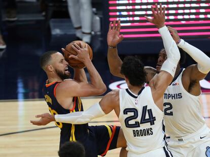 Stephen Curry intenta lanzar ante la oposición de Brooks y Tillman en el partido Warriors-Grizzlies.