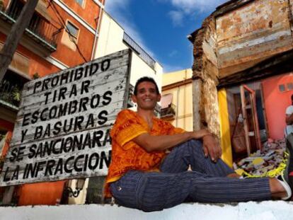 Víctor González posa bajo su fotografía expuesta en una medianera del barrio de El Carmen de Valencia.