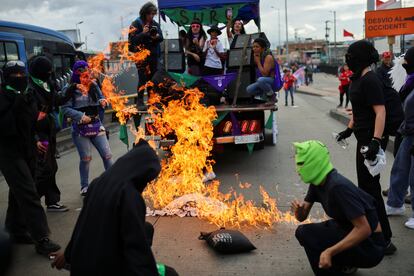 Un grupo enmascarado quema un cartel de protesta durante la marcha del 25 N en Bogotá.