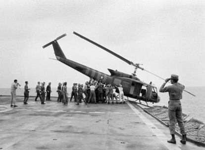 Militares da Marinha norte-americana empurram um helicóptero para o mar, a fim de abrir espaço para receber mais voos em um porta-aviões, em 29 de abril de 1975.