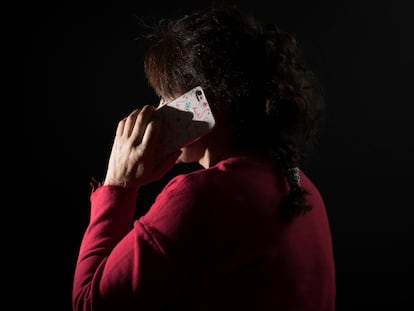 Una mujer víctima de maltrato habla por su teléfono móvil.