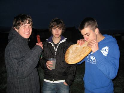 Tres jóvenes reponen fuerza con una torta de pan y chorizo antes de seguir la fiesta.