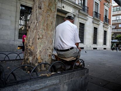 Un hombre sentado sobre las forjas de una jardinera en Madrid.