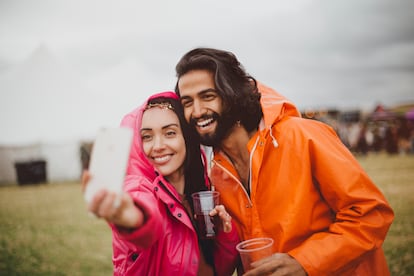 Una pareja joven se hace una 'selfie' antes de un festival en la lluvia.