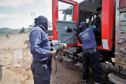 Dos bomberos descargan de un camión equipo para extinguir el fuego en el Cerro Patacón. 