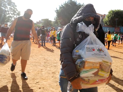 Pessoas carregam sacos de plástico com alimentos para serem distribuídos.