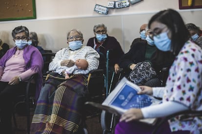 La ómicron está ya entrando con fuerza en las residencias en España, aunque no ha golpeado la salud de los mayores con la virulencia de anteriores olas. En la imagen, una empleada en la sala de lectura, con un periódico, informa a los residentes de las noticias generales y las relacionadas con la incidencia del coronavirus en los centros de mayores para concienciar sobre la necesidad de mantener las medidas de protección.