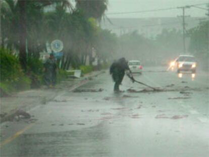 Un trabajador retira los escombros que la tormenta Isidore ha dejado en una carretera en las Islas Caimán.