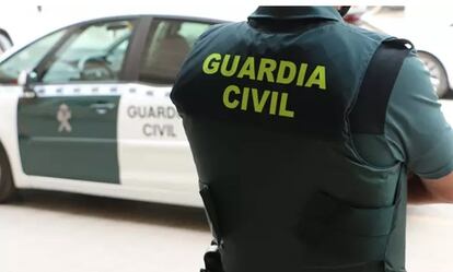 Un agente de la Guardia Civil, de espaldas, junto a un vehículo oficial.