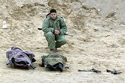 Un soldado israelí, junto a los cadáveres de los dos palestinos que murieron ayer en el tiroteo de Rafah.