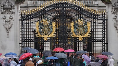 Los turistas se refugian de la lluvia bajo paraguas a las puertas del Palacio de Buckingham, en el centro de Londres.