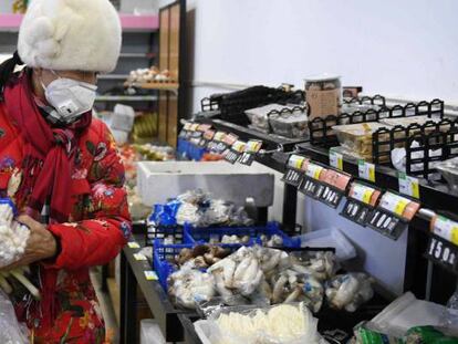  Una mujer compra en una tienda de Pekín, llevando una máscara para evitar el contagio del coronavirus. 