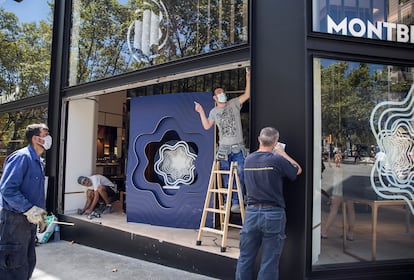 Operarios reparan el escaparate de la joyería Montblanc de paseo de Gràcia, tras sufrir un alunizaje.