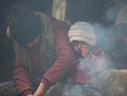 People sit near a fire in a migrants' makeshift camp on the Belarusian-Polish border in the Grodno region, Belarus November 12, 2021. Leonid Scheglov/BelTA/Handout via REUTERS  ATTENTION EDITORS - THIS IMAGE HAS BEEN SUPPLIED BY A THIRD PARTY. NO RESALES. NO ARCHIVE. MANDATORY CREDIT.