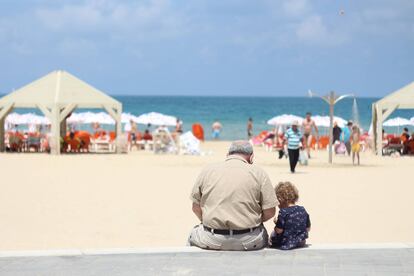 Un abuelo con su nieta en el poyete de un paseo marítimo. UNSPLASH