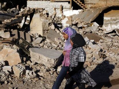 Dos niñas sirias caminan junto a los escombros de una casa derribada durante un bombardeo de las fuerzas pro-régimen.
