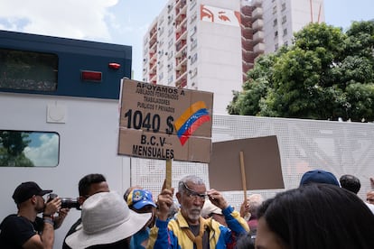 Un manifestante jubilado alza su cartel frente a un camión antimotines.