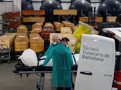 Dos empleados trasladan los restos de una víctima de covid en un tanatorio de Barcelona, el pasado lunes.