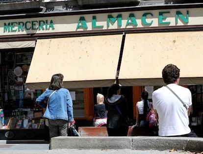 Varios clientes hacen cola para entrar a una tienda, en Madrid.  