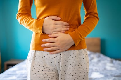 A young woman is having pain in her stomach and holding it with both hands