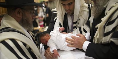 Un judío ortodoxo sostiene a su hijo durante su circuncisión en Jerusalén.