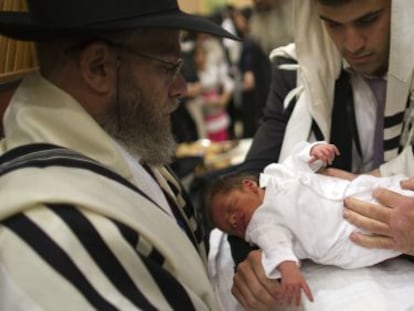 Un judío ortodoxo sostiene a su hijo durante su circuncisión en Jerusalén.