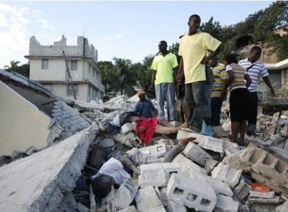 Una mujer semienterrada entre los escombros reclama la ayuda de algunos supervivientes poco después del terremoto en Puerto Príncipe.