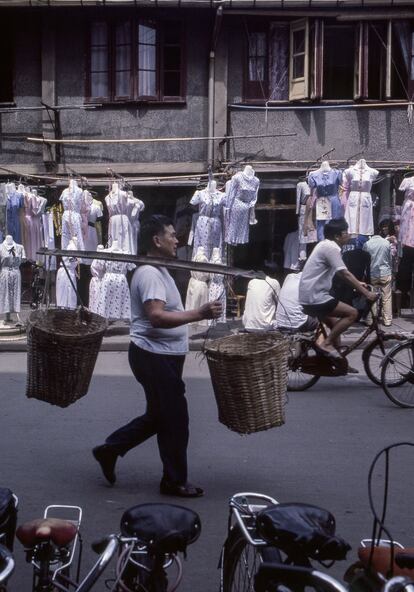 Un hombre lleva unos cestos en una calle de Shanghái.