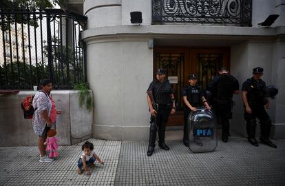 Una mujer y un niño afuera de las oficinas del Ministerio de Capital Humano, resguardado por la policía.