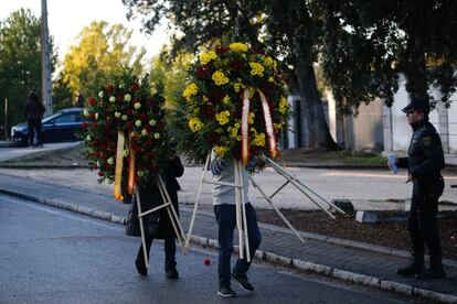 Dos personas llevan coronas al cementerio de El Pardo-Mingorrubio antes del traslado de los restos exhumados de Franco, en octubre de 2019.