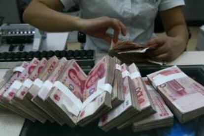 Un empleado bancario cuenta billetes en un banco en China. EFE/Archivo