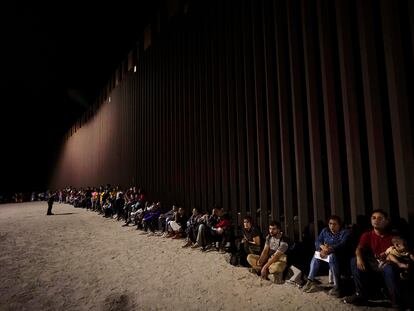 Migrantes esperan a lo largo del muro fronterizo luego de cruzar desde México a EEUU, cerca de Yuma (Arizona).