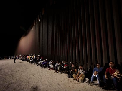 Migrantes esperan a lo largo del muro fronterizo luego de cruzar desde México a EEUU, cerca de Yuma (Arizona).