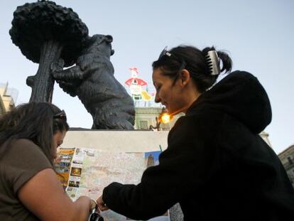 Dos turistas consultan un mapa en la Puerta del Sol.