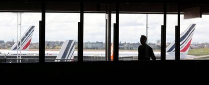 FILE PHOTO: A passenger walks as Air France planes are parked on the tarmac at Orly Airport near Paris as Air France pilots, cabin and ground crews unions call for a strike over salaries