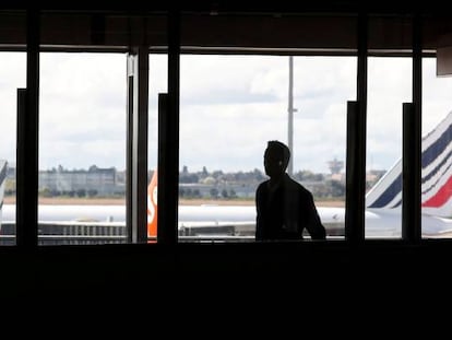 FILE PHOTO: A passenger walks as Air France planes are parked on the tarmac at Orly Airport near Paris as Air France pilots, cabin and ground crews unions call for a strike over salaries