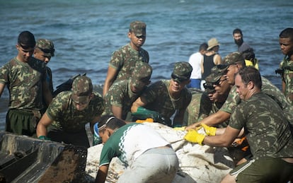 Na foto, soldados do Exército trabalham para colocar um saco com resíduos de óleo acumulado no trator. 