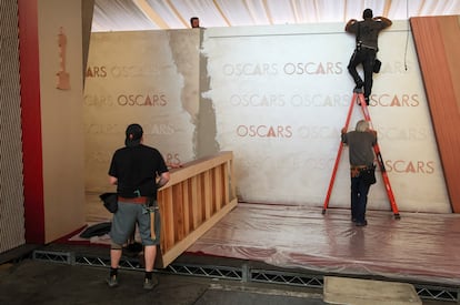 Varios trabajadores se afanan en preparar la alfombra roja de los Oscar, en Hollywood Boulevard, en Los Ángeles, California, el 26 de febrero de 2025.