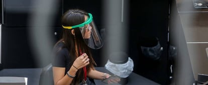 Una mujer protegida con una pantalla protectora trabajando.