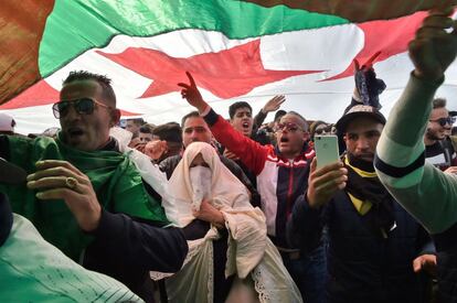 Un grupo de manifestantes argelinos protesta bajo una bandera nacional.