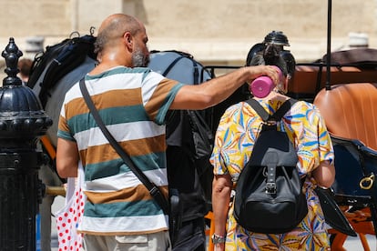 Unos turistas intentan refrescarse en Sevilla durante la ola de calor de este mes de agosto.