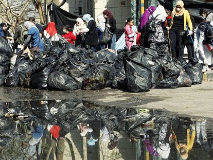Un grupo de voluntarios recoge bolsas de basura en la plaza de la Liberación de El Cairo.