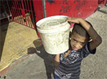 Un niño de siete años acarrea un cubo de agua en un barrio de Villa María (Santo Domingo). El acceso al agua potable de millones de personas es un reto de la Cumbre de la Tierra.