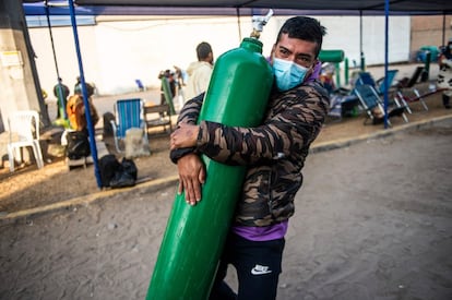 Un hombre carga con un tanque de oxígeno vacío mientras llega a la cola para rellenarlo en Villa El Salvador, en las afueras del sur de Lima.