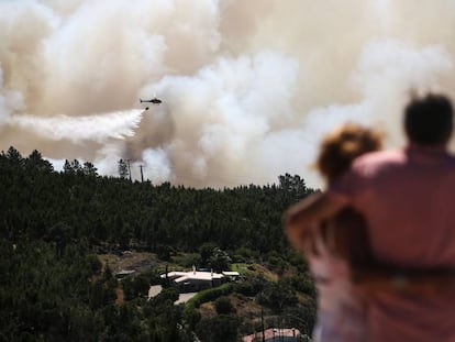 Una pareja contempla este miércoles cómo un helicóptero trabaja en las labores de extinción del incendio en el Algarve (Portugal).