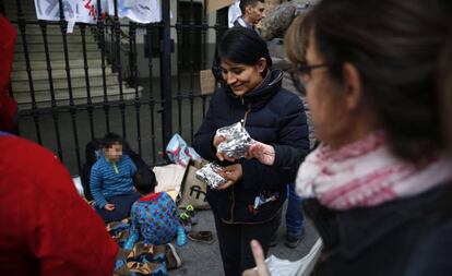 Locals give food to a Peruvian family seeking a bed outside Madrid’s Samur Social.