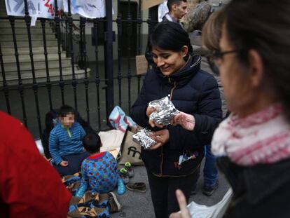Locals give food to a Peruvian family seeking a bed outside Madrid’s Samur Social.